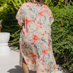 Back view of plus-size model walking poolside in bold floral Springtime Kaftan – white maxi dress with kimono sleeves and side slits