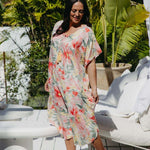 Side view of model in bold floral Springtime Kaftan with flowing kimono sleeves and white background – resort wear dress