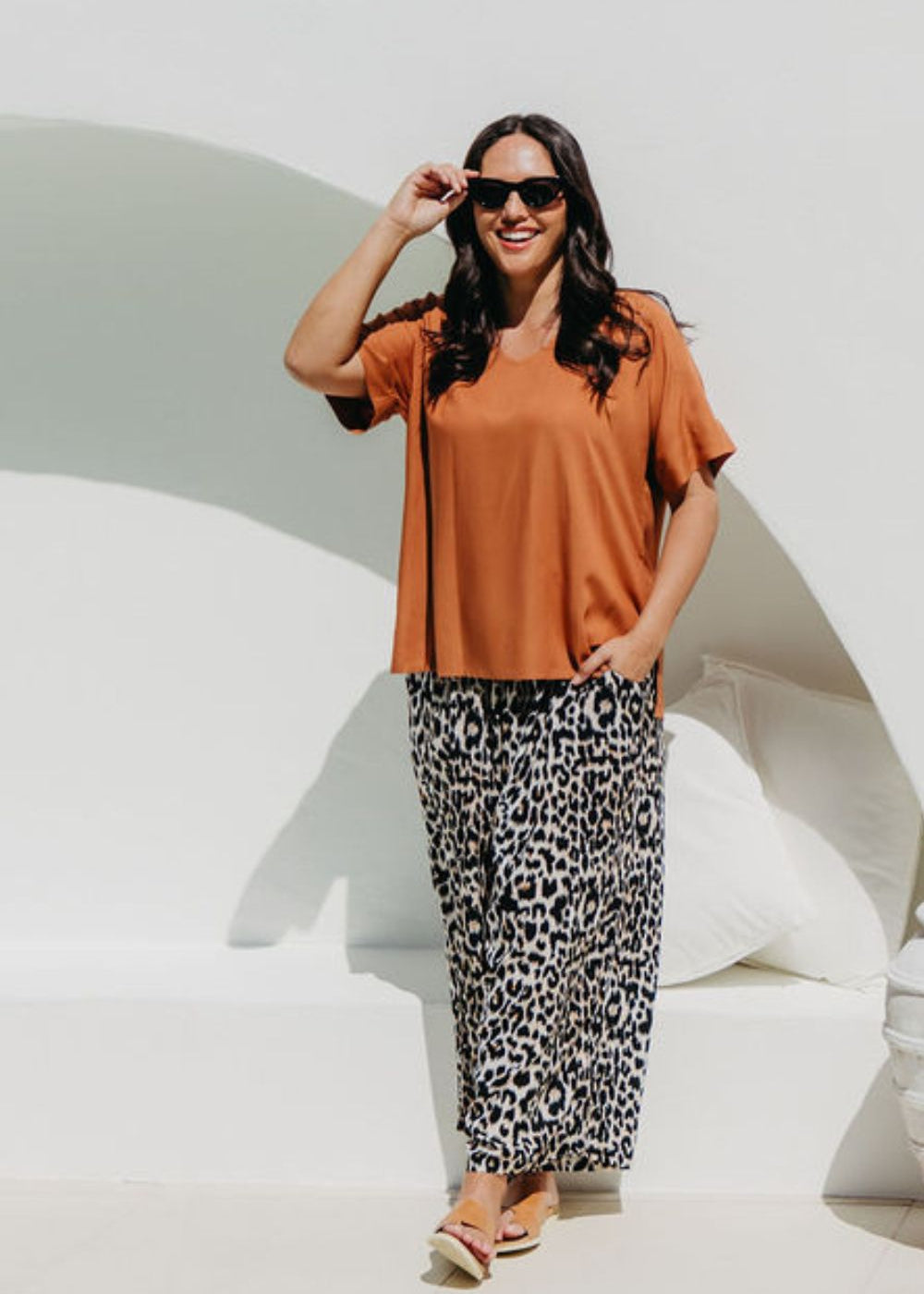 Woman wearing a mocha brown top and leopard print pants poolside