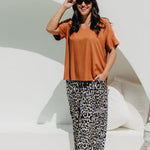 Woman wearing a mocha brown top and leopard print pants poolside