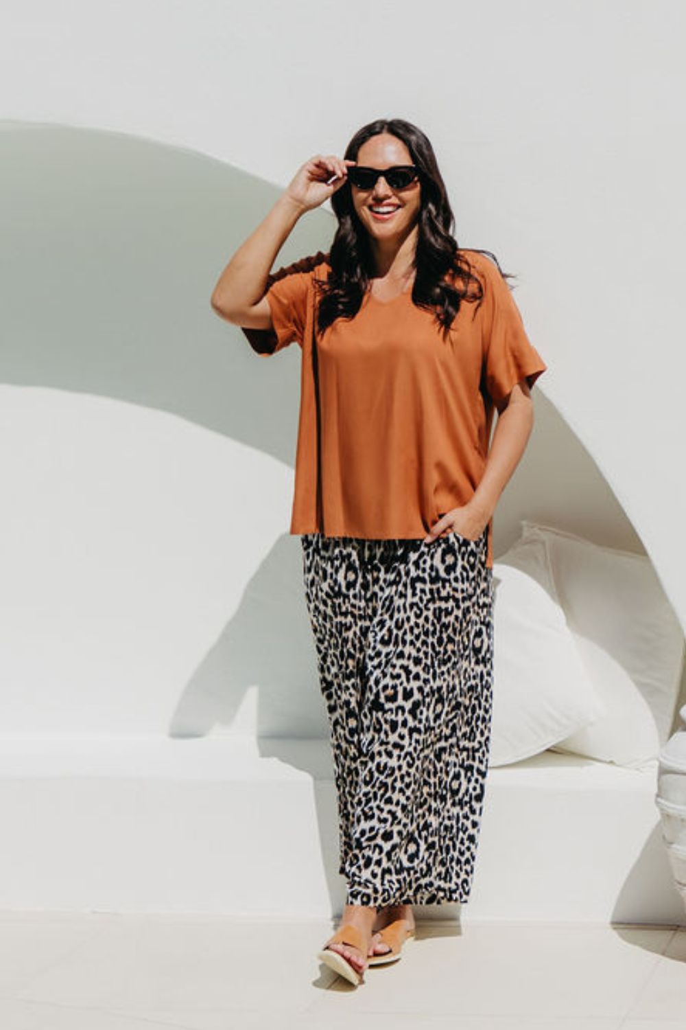 Woman wearing a mocha brown top and leopard print pants poolside