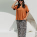 Woman wearing a mocha brown top and leopard print pants poolside