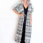 Geo print maxi kimono jacket styled over black maxi kaftan dress on size 8–10 model