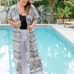 Size 16 model wearing geo print maxi kimono jacket layered over white cotton pants and black cami