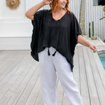 full length view of a woman wearing a black kaftan top half tucked on a pool deck, size S/M model