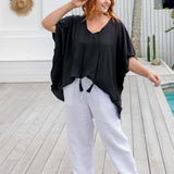 full length view of a woman wearing a black kaftan top half tucked on a pool deck, size S/M model